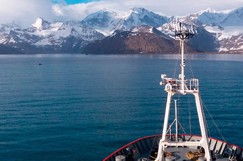 Bow of research ship with ice capped mountains of south giorgia in the background