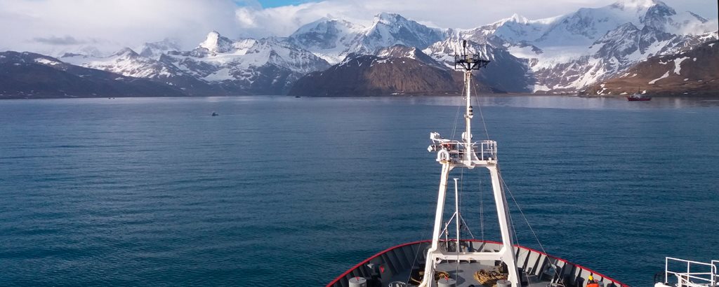 Bow of research ship with ice capped mountains of south giorgia in the background